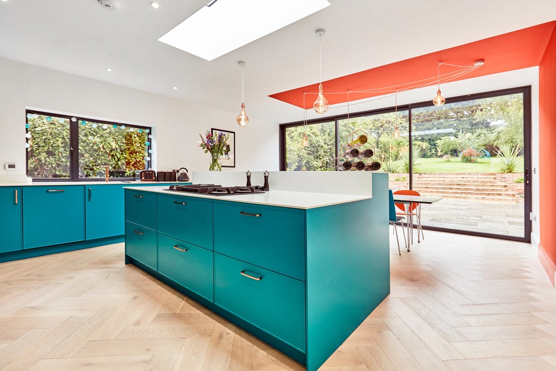 Colourful teal kitchen with orange feature wall